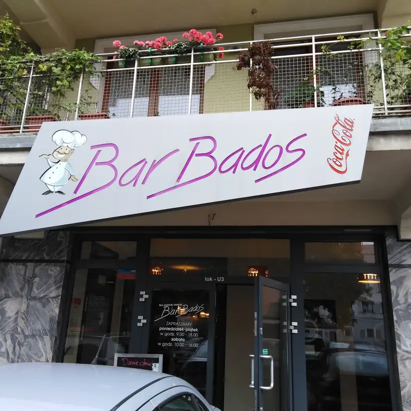 Wejście do BarBados z różowym szyldem na parterze kamienicy